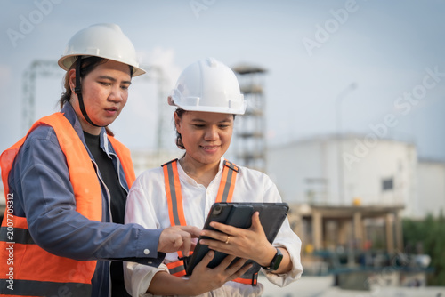 Φωτογραφία Two engineers in hard hats review data on a tablet