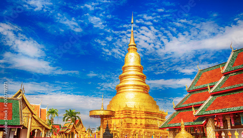 Majestic golden pagoda of Wat Phra That Hariphunchai under a bright blue sky in Lamphun.