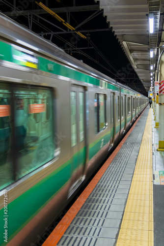 Fotografie green line commuter train arriving at platform at night in tokyo