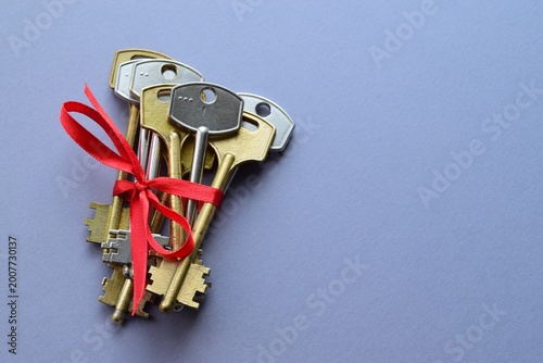 Pile of old keys with a red ribbon on a gray background