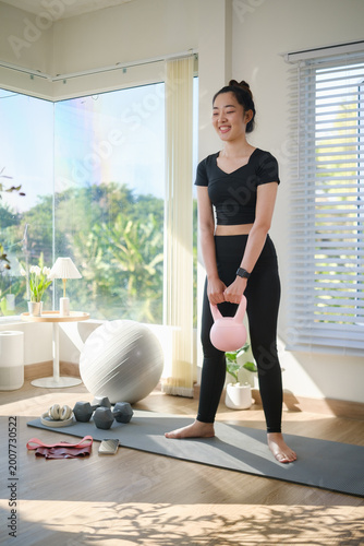 Canvastavla Young woman exercising at home, squat with a kettlebell in a bright and modern living space