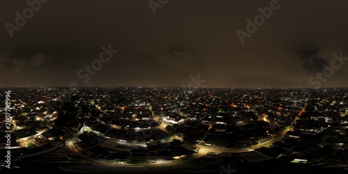 Cuadro en lienzo Wide panoramic aerial night view of a glowing city skyline with dense residential housing and a lit mosque minaret