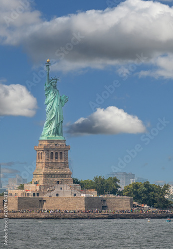 New york, usa august 16,2024. Statue of liberty on liberty island rises against a bright blue sky with scattered white clouds, symbol of freedom and democracy