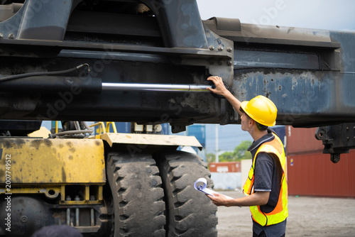 the operation or engineer construction supervisor is checking on heavy machine and equipment checklist form with crane truck as background. Industrial safety working in action