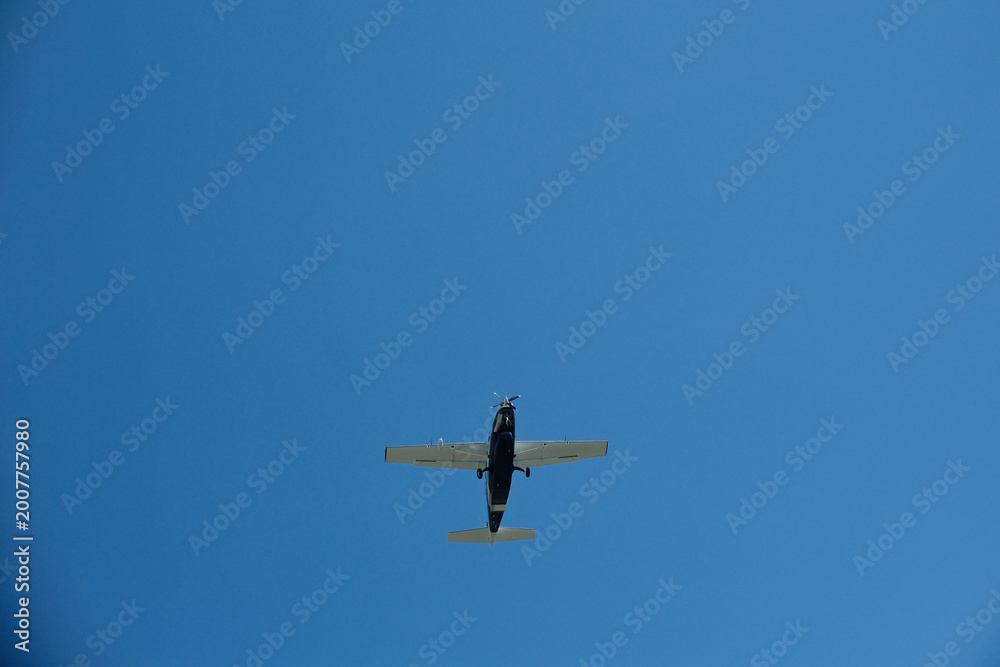 Fototapeta premium Low Angle View of a Single-Propeller Plane Flying in Clear Blue Sky