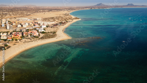 Drone view of Sal Rei town,sandy beach and yacht moored in the green ocean, background volcanic mountain and desert,Sal Rei , Boa Vista island, Cape Verde.
