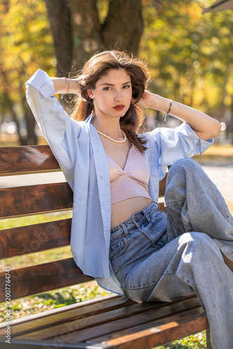 Young beautiful woman sitting on a bench in an autumn park