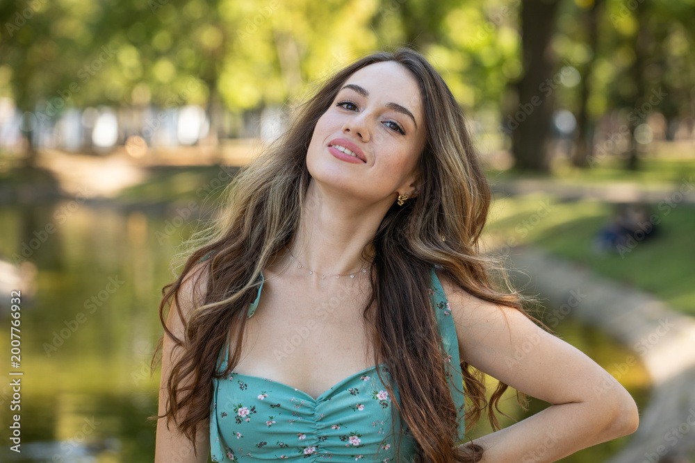 Fototapeta premium Full body portrait of a young beautiful woman in a turquoise dress