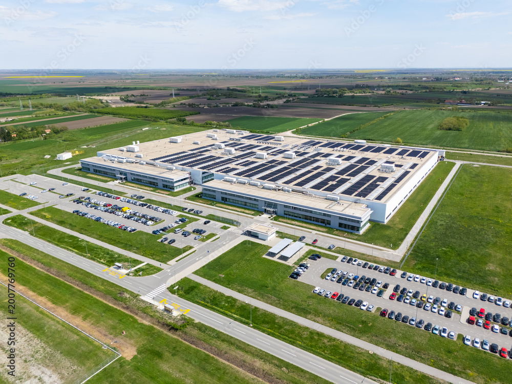 Obraz premium Aerial view of a modern factory with solar panels and energy storages on the roof
