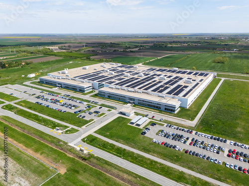 Aerial view of a modern factory with solar panels and energy storages on the roof