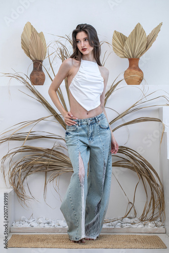 Fashion portrait of a young beautiful brunette girl in blue jeans