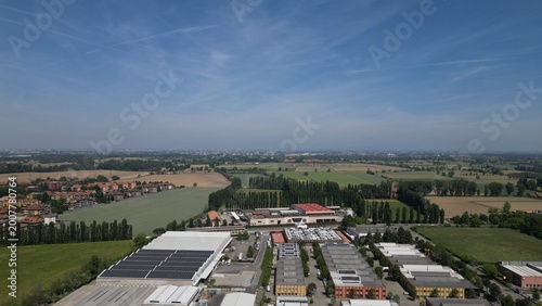 Urban Harmony: An aerial view showcases the convergence of an industrial zone and agricultural lands, blending urban and rural landscapes under a serene sky. 