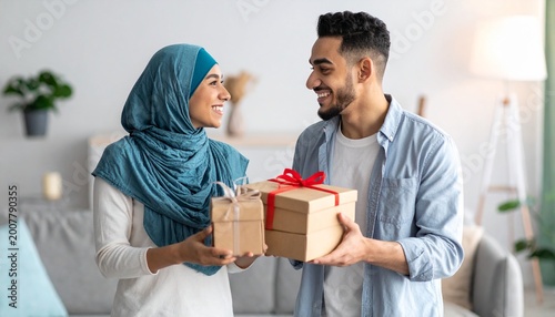 Loving Muslim couple exchanging gifts at home, celebrating special occasion.