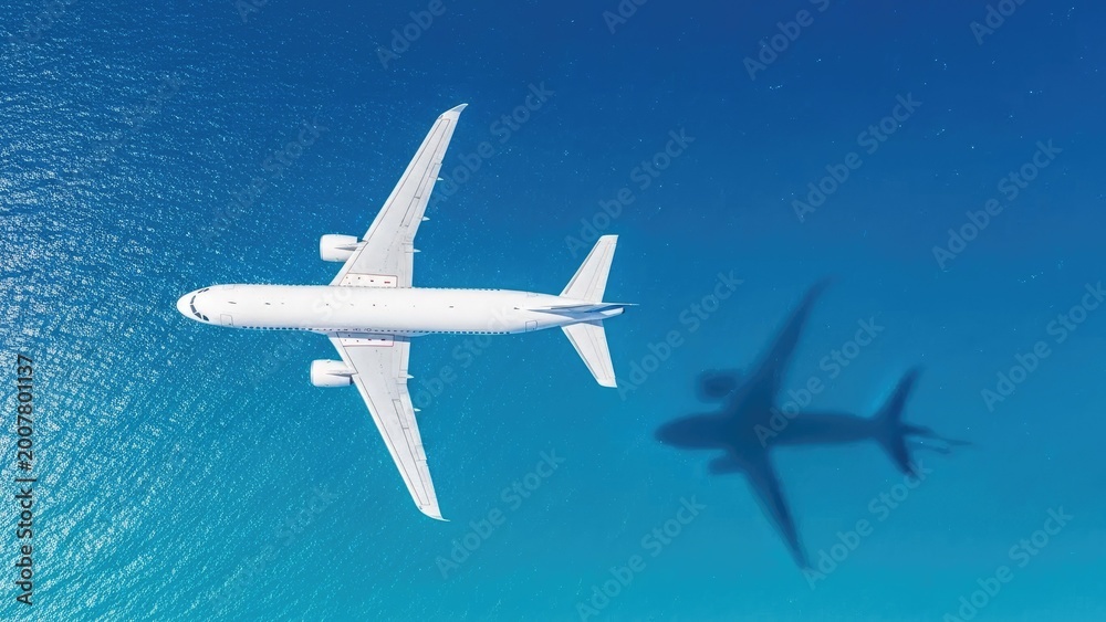 Fototapeta premium commercial airplane flying above drone shadow over ocean travel concept
