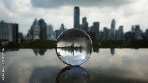 Schilderij op canvas A transparent crystal, glass ball reflecting an inverted modern bangkok city skyline, The image symbolizes a new perspective of the world smart cities, and the connection between urban development
