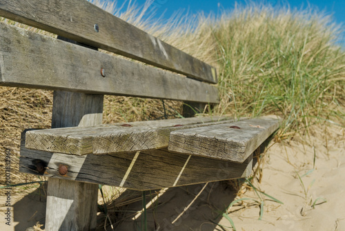 Εκτύπωση καμβά Close-up of a weathered wooden park bench in the sand dunes of Den Helder, Netherlands