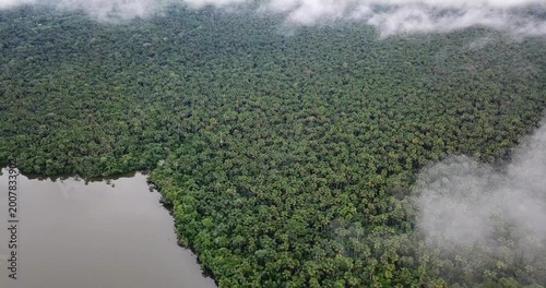 Aerial view of Amazon rainforest with clouds drifting over canopy and river near Iquitos Peru