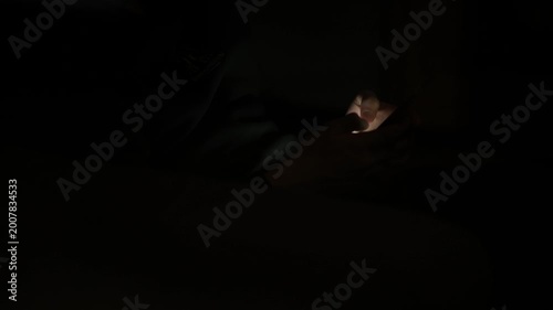 Person using smartphone at night, scrolling on mobile phone, digital lifestyle concept