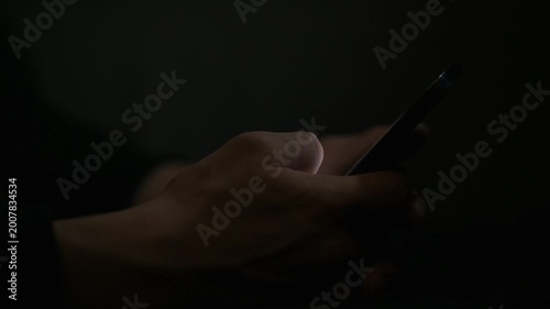 Close-up of hand scrolling on smartphone in dark, social media and mobile usage concept