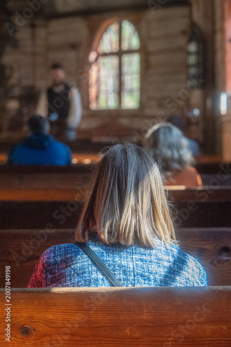 People Sitting in Wooden Church Pews During Quiet Service with Speaker in Historic Interior,