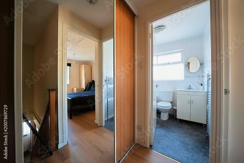 Interior view of a modern apartment hallway with access to a bedroom, bathroom, and a set of stairs leading downwards