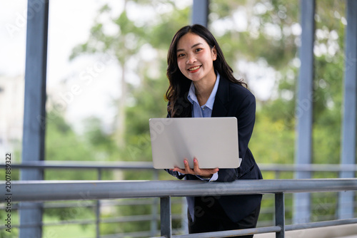 Young asian businesswoman using laptop smiling outdoors