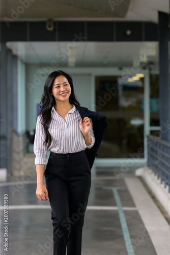 Confident Asian business woman smiling and walking in office building
