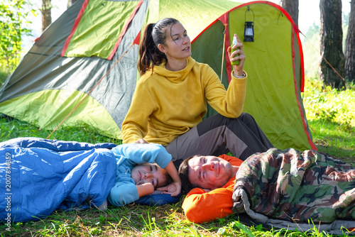 Mother at tent with spray bottle, providing insect bite protection for family, safe holidays, outdoors and recreation.