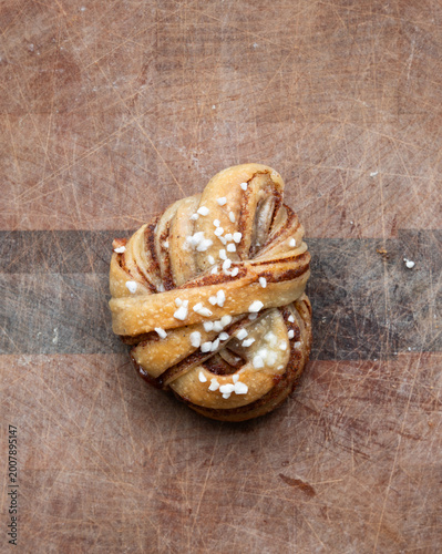 Freshly baked artisan Kanelbulle, a swedish cinnamon bun, on a wood cutting board