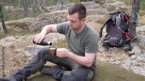 Hiker Resting with Hot Drink in Rocky Forest Camp