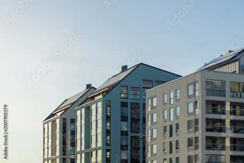 Modern residential apartment buildings with contemporary architecture, large windows, and solar panels on their roofs