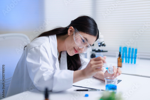 Konstfotografi Female researcher pouring chemical liquid from a pipette into a beaker with blue