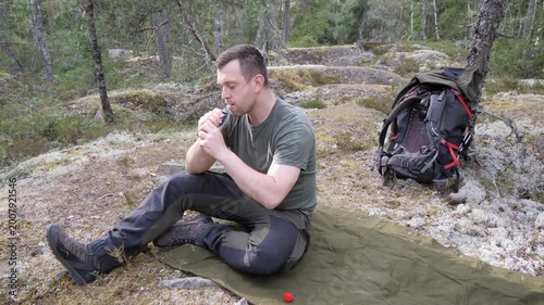 Hiker resting on camping mat in forest with backpack