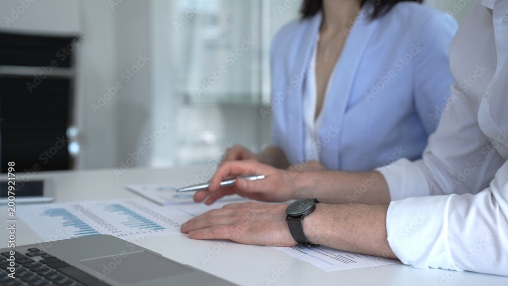 Fototapeta premium Business professionals analyzing financial reports and presenting data during an office meeting, discussing market trends and strategic planning