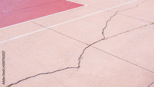 Crack line texture on damaged exposed aggregate stone floor surface of outdoors sport court background