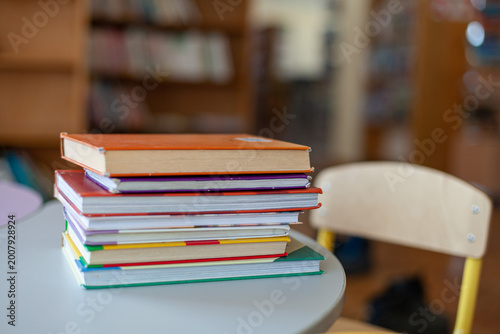 Tableau sur toile Colorful stack of hardcover books on round table in classroom or library interior