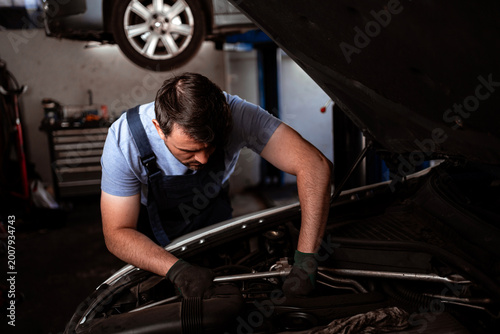 Obraz na plátně Mechanic works on car engine in garage during daytime to perform repairs and mai