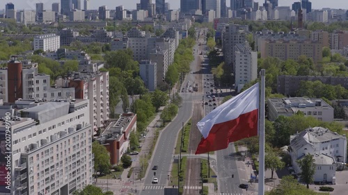 Warsaw skyline from drone with a large Polish flag waving above the city on a clear day