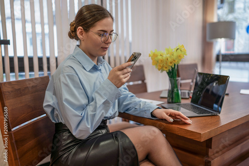 Φωτογραφία Businesswoman checking smartphone messages while sitting at her sleek wooden off
