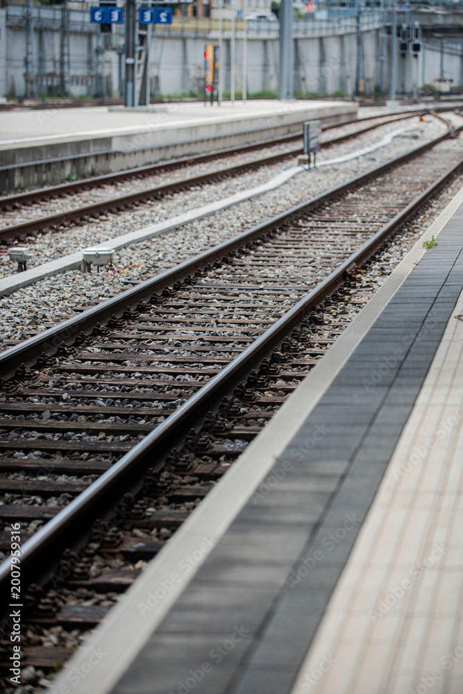 Fototapeta premium Railway station platform with rail track and railway transport infrastructure forming industrial railway background and train travel transportation concept.