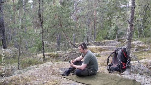 Hiker resting with headphones in a quiet pine forest
