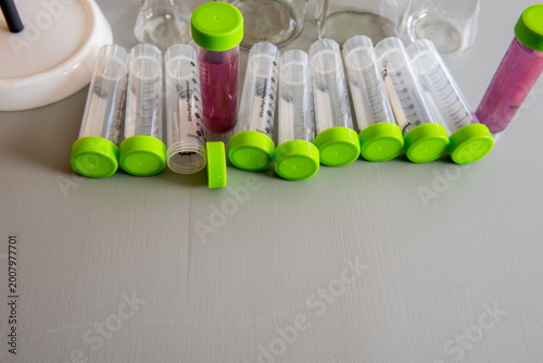 laboratory test tubes with green caps and sample liquids on table