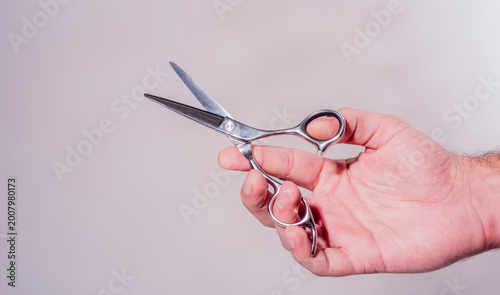 Hairdresser with barber tools in hand. Classic barber scissors. Elegant barbershop interior. Grooming background.