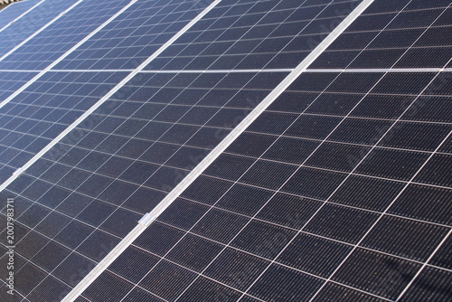 Close-up of solar panels with blue photovoltaic cells and silver frames, displaying a repetitive grid pattern for renewable energy concepts.