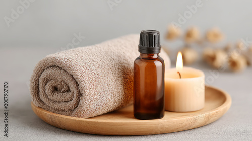 Spa and relaxation concept with wooden tray featuring towel roll, essential oil dropper, and candle