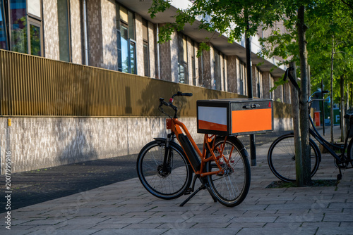 Orange Electric Delivery Bike with Cargo Box Parked on Urban Sidewalk, Netherlands.