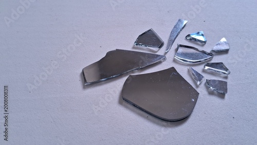 Foto Sharp shards of a broken mirror scattered across a flat neutral surface creating