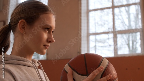 Εκτύπωση καμβά Young female athlete with a ponytail wearing a hoodie in a gym, holding a basket