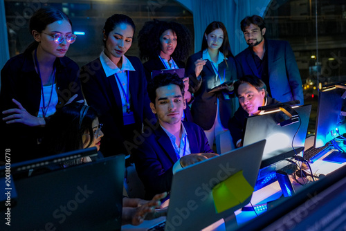 Bild auf Leinwand Friendly senior East Asian employee smiling genuinely while working late at night in a dimly lit office