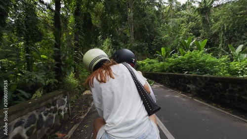 Woman riding on a scooter through a tropical jungle road in bali